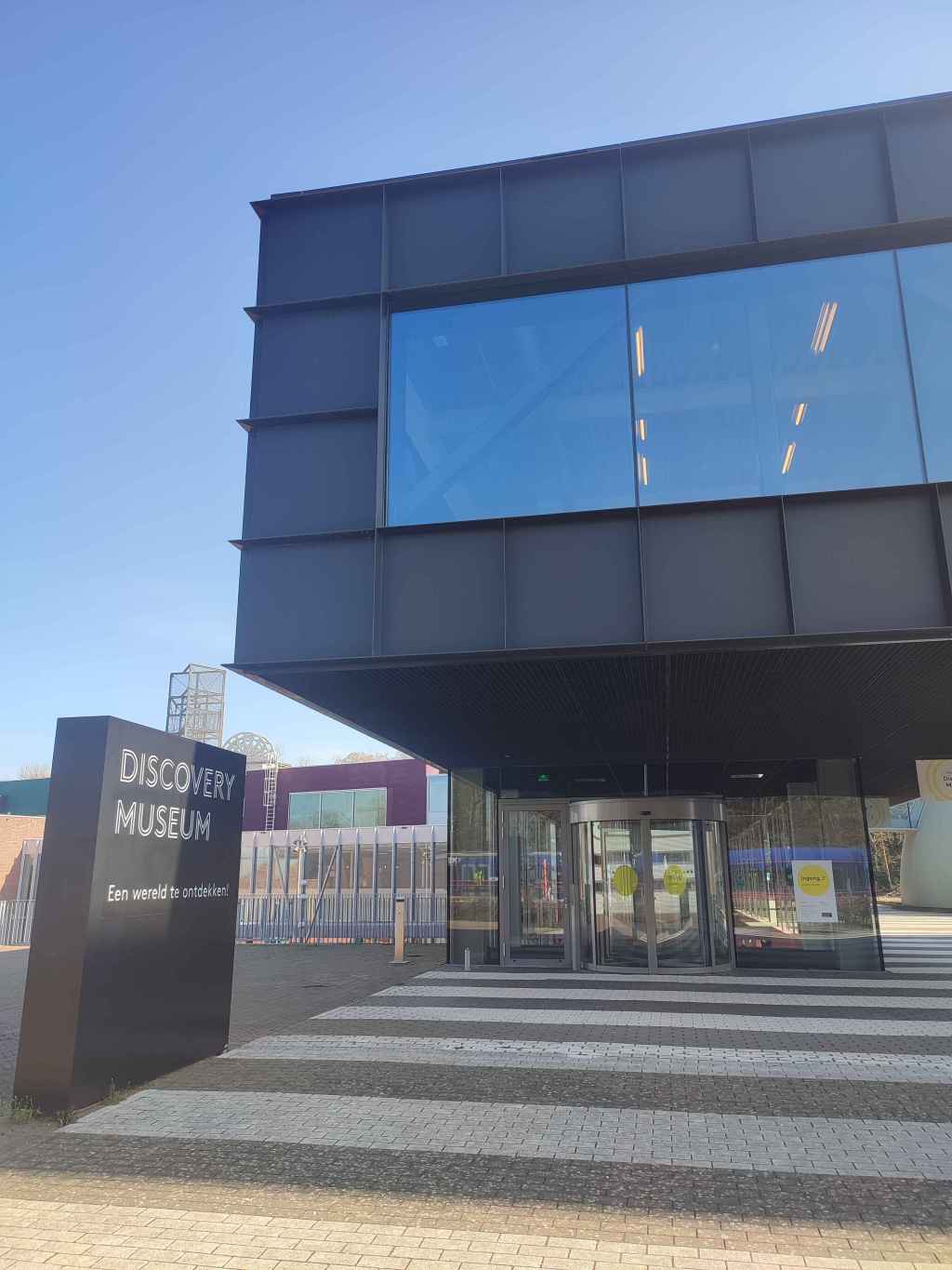 The exit of the Discovery Museum. A modern looking sign in the bottom left says the museums name, while the building climbs to the right